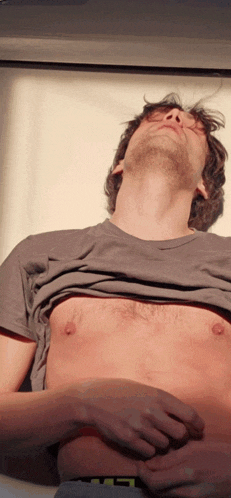 a shirtless man with his eyes closed is laying on a white surface