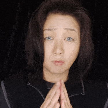 a woman with her hands folded looks at the camera