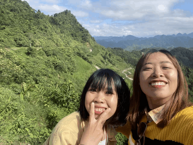two girls are posing for a picture in front of a mountain