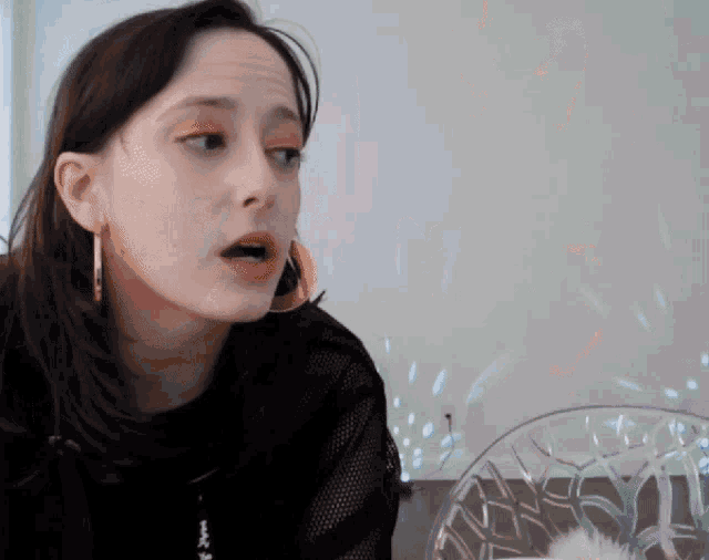 a woman wearing hoop earrings is sitting in front of a plate