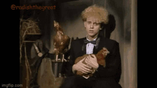 a man in a tuxedo is holding a chicken