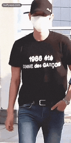a man wearing a mask and a black t-shirt is walking down the street .