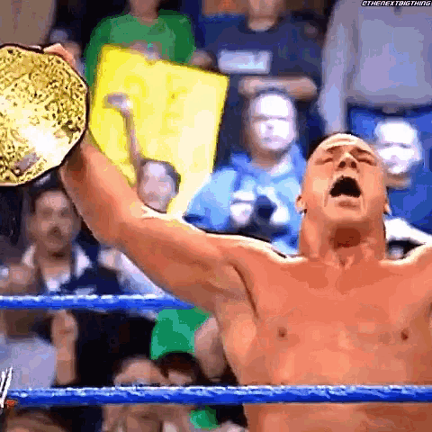 a shirtless wrestler is holding a championship belt in the air .