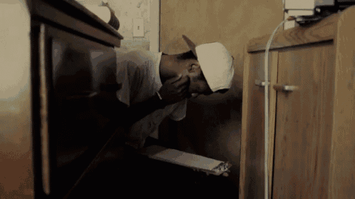a man in a white hat is sitting in a corner of a room