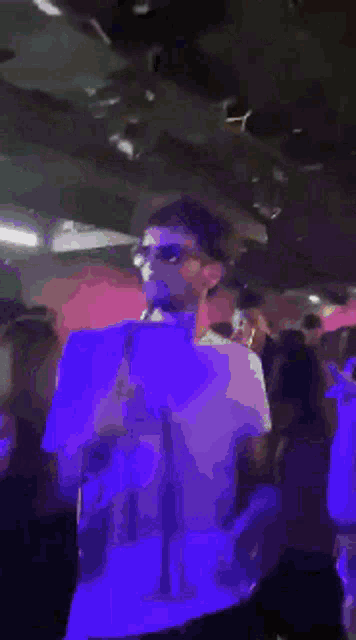 a man in a purple shirt is standing in a crowd