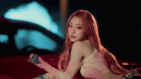 a woman with pink hair is sitting on the back of a red car .