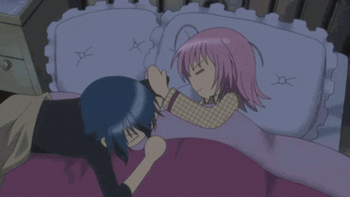 a girl with pink hair and a star on her head is laying next to another girl