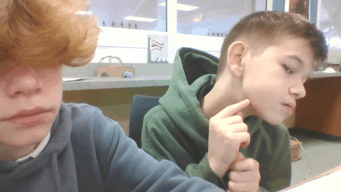 a boy with red hair is sitting next to another boy