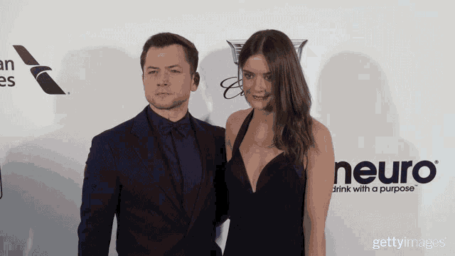 a man and a woman stand on a red carpet that says neuro drink with a purpose