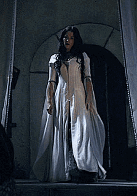 a woman in a white dress stands in front of a door