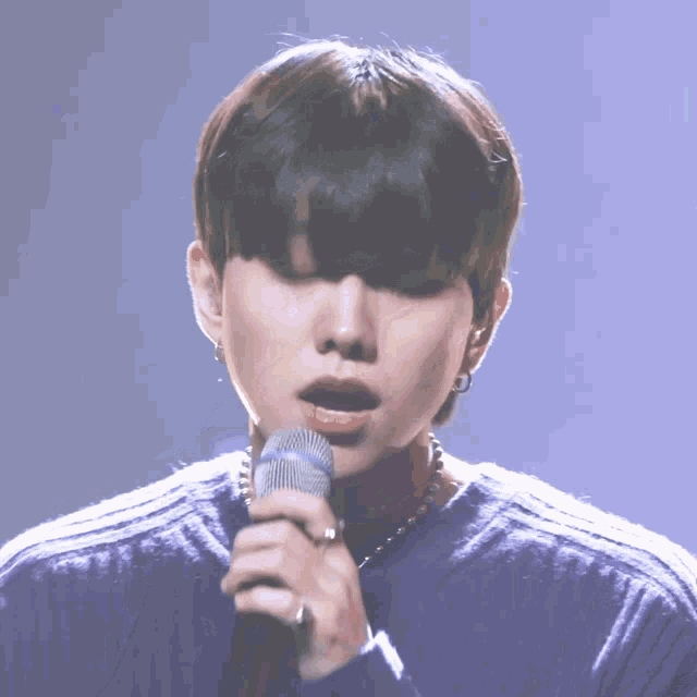 a man singing into a microphone with a ring on his finger