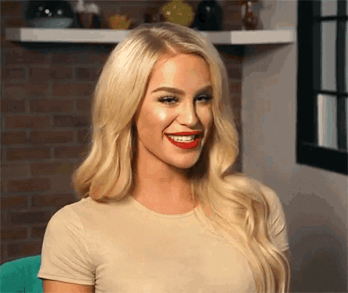 a woman with blonde hair and red lipstick is smiling for the camera .