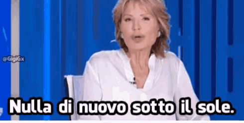 a woman in a white shirt is sitting in front of a blue wall and says nulla di novo sotto il sole .