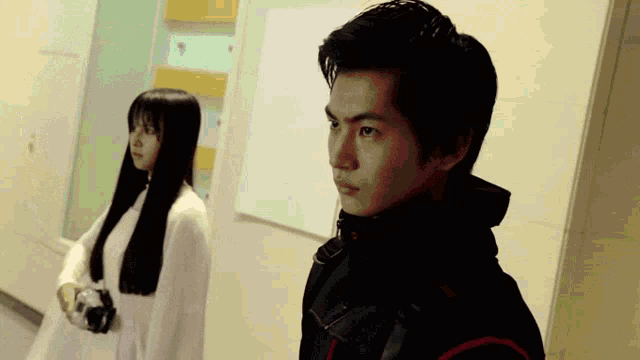 a man and a woman are standing in a hallway .