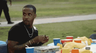 a man in a black shirt is sitting at a table eating a snack .