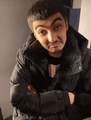 a man in a black jacket has his arms crossed and looks at the camera