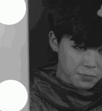 a black and white photo of a person looking at themselves in a mirror .