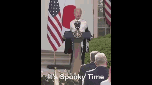 a man stands at a podium with the words " it 's spooky time " written below him