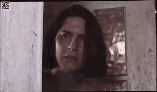 a woman is standing in a doorway looking at the camera with a serious look on her face .