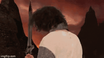 a man in a knight 's costume is holding a sword in front of mountains .
