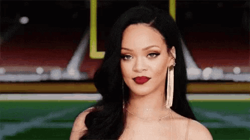 a close up of a woman 's face with a football field in the background .