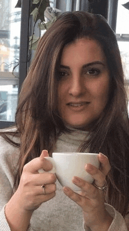a woman is holding a cup of coffee and smiling .