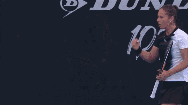 a woman flexes her fist in front of a 100 years sign