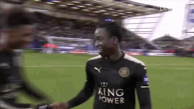 a soccer player wearing a black king power shirt