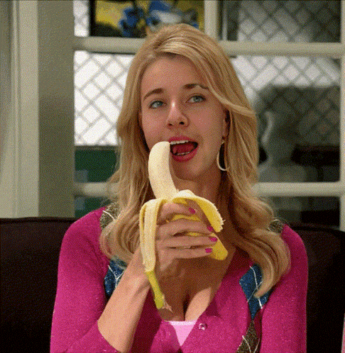 a woman in a pink sweater eating a banana