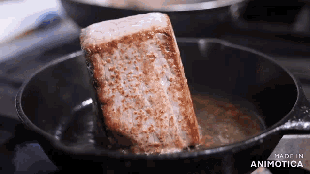 a piece of meat is being cooked in a skillet with the words made in animotica visible