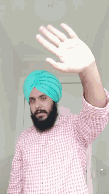 a man with a beard wearing a pink and white checkered shirt and a green turban