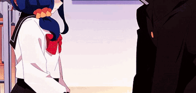 a girl in a school uniform is standing next to a man in a black suit .