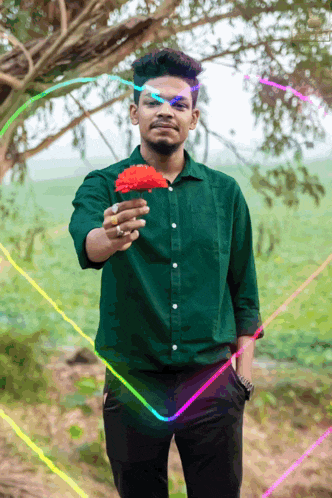a man in a green shirt holds a red flower