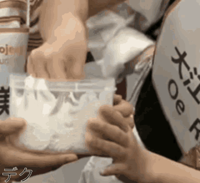 a person is holding a plastic container in their hands with chinese writing on it