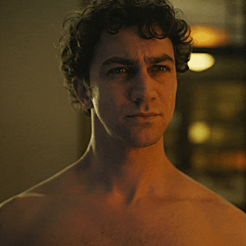 a man without a shirt looks at the camera