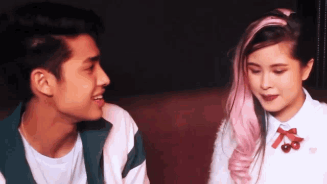 a man and a woman are sitting next to each other and looking at each other .