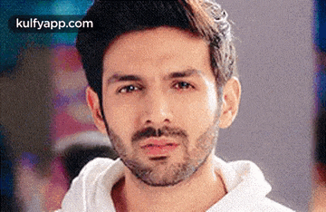 a close up of a man with a beard wearing a white shirt and a white hoodie .