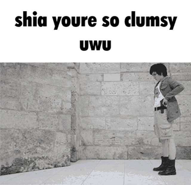 a person standing in front of a brick wall with the words " shia youre so clumsy uwu "