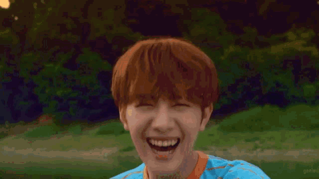 a young boy with red hair is wearing a blue and orange striped shirt .