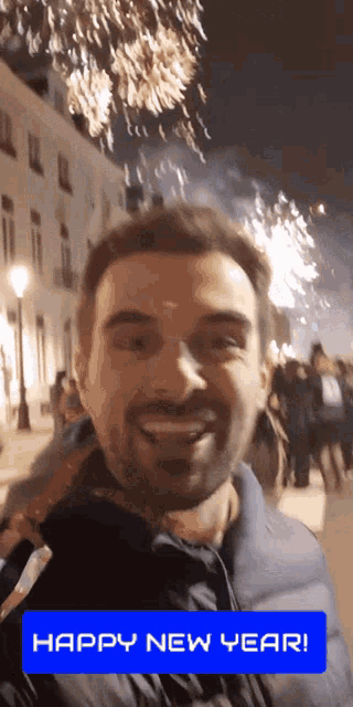 a man is smiling in front of a fireworks display with the words happy new year on the bottom