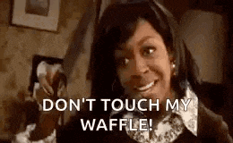 a woman is holding a waffle in her hand and smiling .