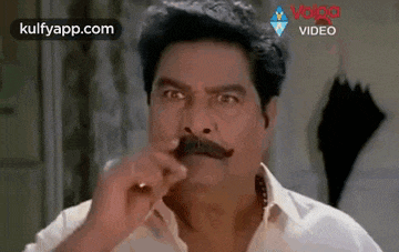 a man with a mustache is holding his nose .