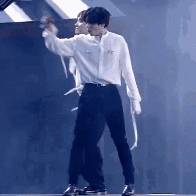 a man in a white shirt and black pants is dancing with another man