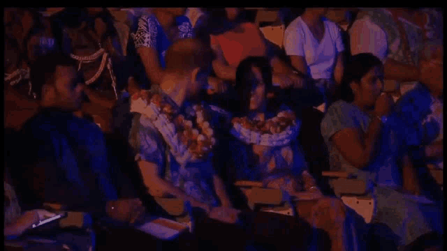 a group of people are sitting in a dark room watching a concert .