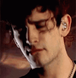 a close up of a man 's face with a shadow on his face and ear buds .