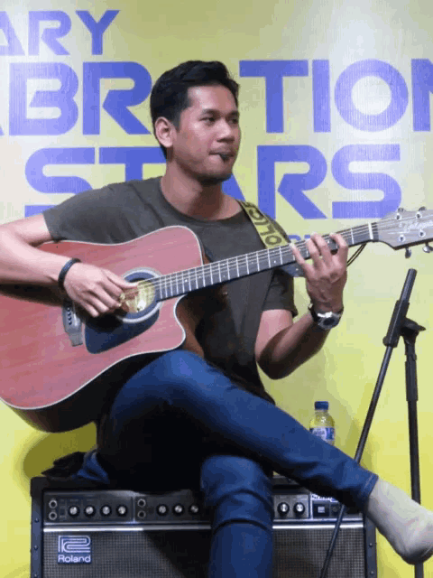 a man playing an acoustic guitar in front of a sign that says vibration stars