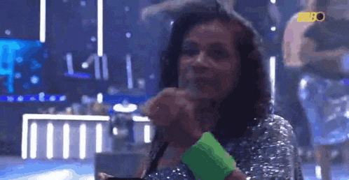 a woman is holding a green wristband in front of a microphone .