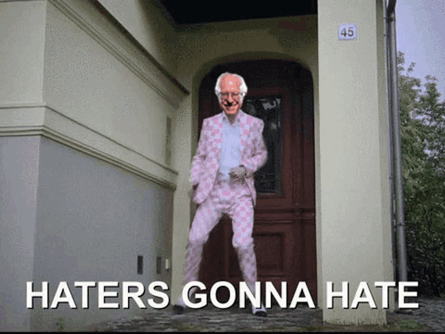 a man in a pink suit is dancing in front of a door with the words haters gonna hate written below him