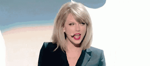 a woman in a suit is standing in front of a microphone and making a funny face .