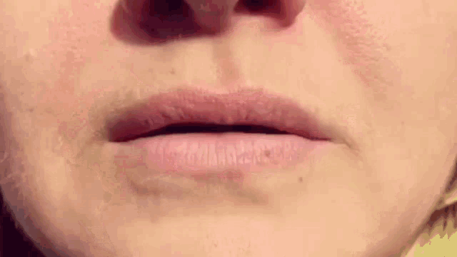 a close up of a woman 's lips with a yellow sweater on .